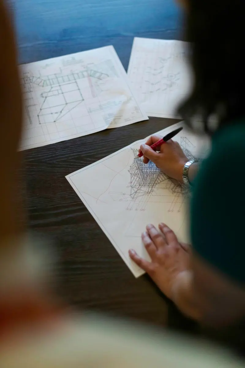 a person's hands as they work on an architectural drawing.
